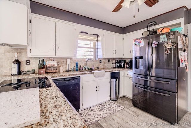 kitchen featuring black appliances, light wood-type flooring, light stone counters, decorative backsplash, and white cabinetry