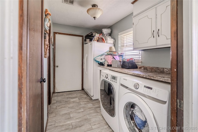 clothes washing area with visible vents, wood tiled floor, cabinet space, a textured ceiling, and washer and dryer