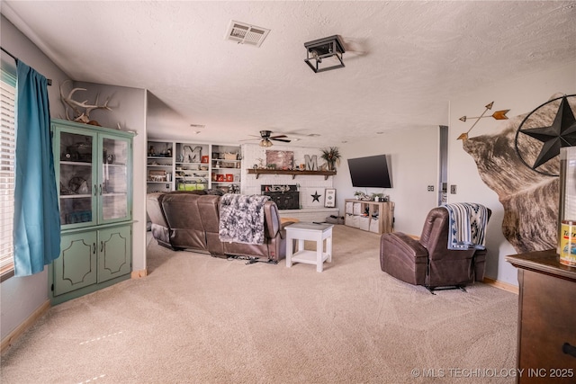 living room featuring visible vents, light carpet, a fireplace with raised hearth, a textured ceiling, and ceiling fan