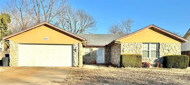 ranch-style house with stone siding, roof with shingles, concrete driveway, and an attached garage