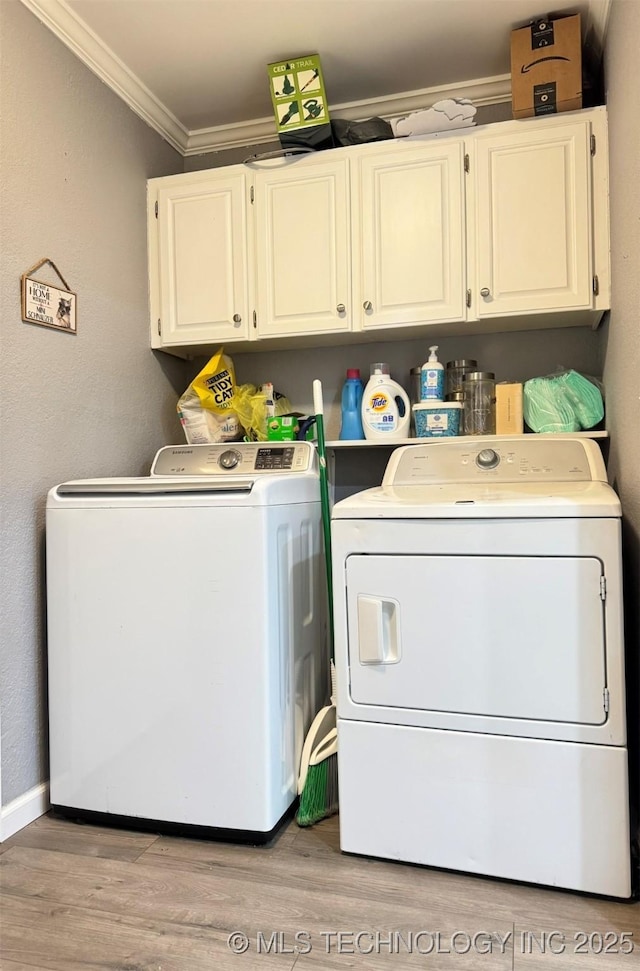 laundry area featuring crown molding, cabinets, light hardwood / wood-style floors, and washing machine and dryer