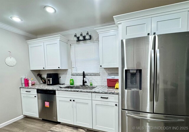 kitchen featuring white cabinetry, stainless steel appliances, light stone countertops, and sink