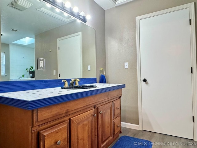 bathroom with vanity, a skylight, and wood-type flooring