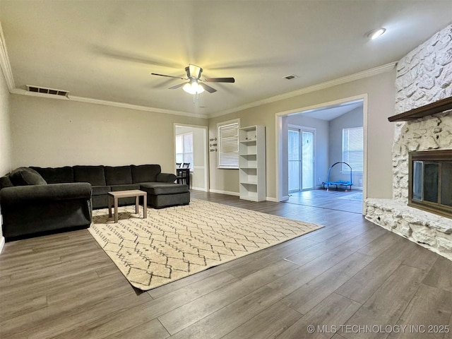 living room with hardwood / wood-style flooring, ceiling fan, a fireplace, and crown molding