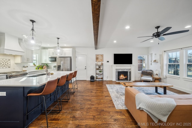 living room featuring beamed ceiling, ceiling fan, sink, and dark hardwood / wood-style flooring