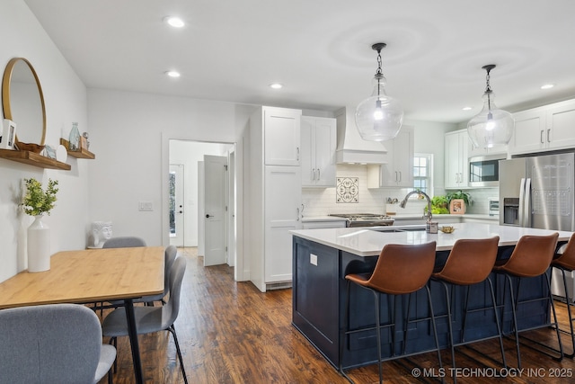 kitchen featuring sink, dark wood-type flooring, appliances with stainless steel finishes, an island with sink, and white cabinets