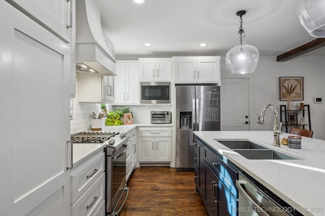 kitchen featuring sink, appliances with stainless steel finishes, custom range hood, white cabinets, and decorative light fixtures