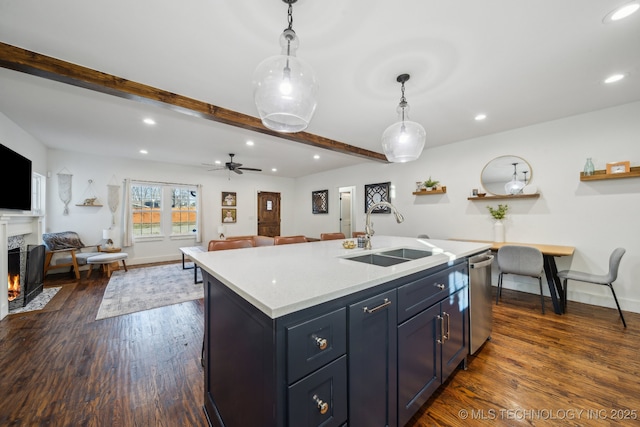 kitchen featuring decorative light fixtures, an island with sink, sink, a premium fireplace, and beam ceiling