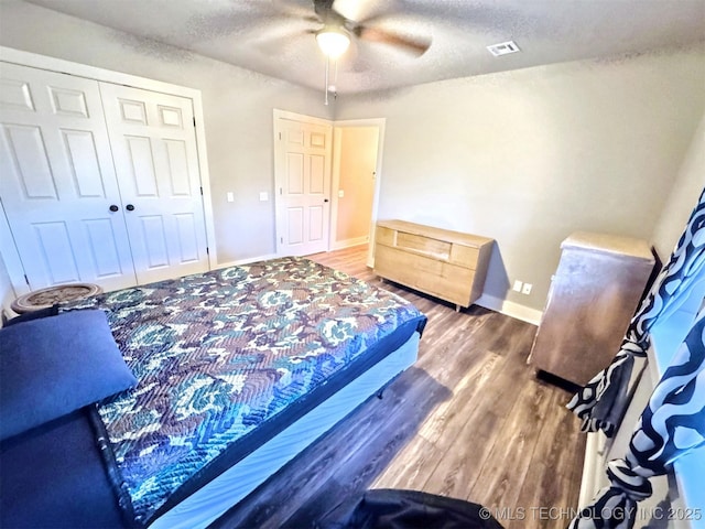 bedroom featuring a textured ceiling, wood finished floors, visible vents, and baseboards