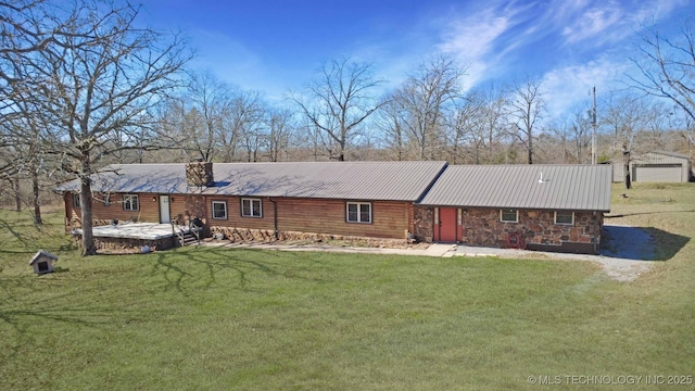 view of front of property with metal roof, stone siding, a chimney, and a front yard