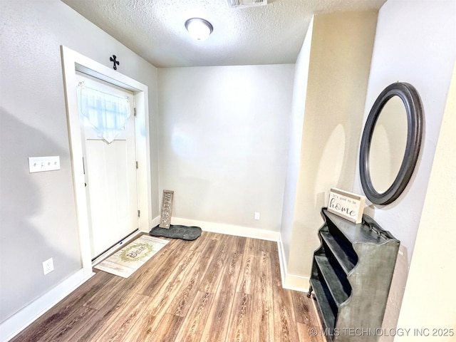 entrance foyer with a textured ceiling, wood finished floors, and baseboards