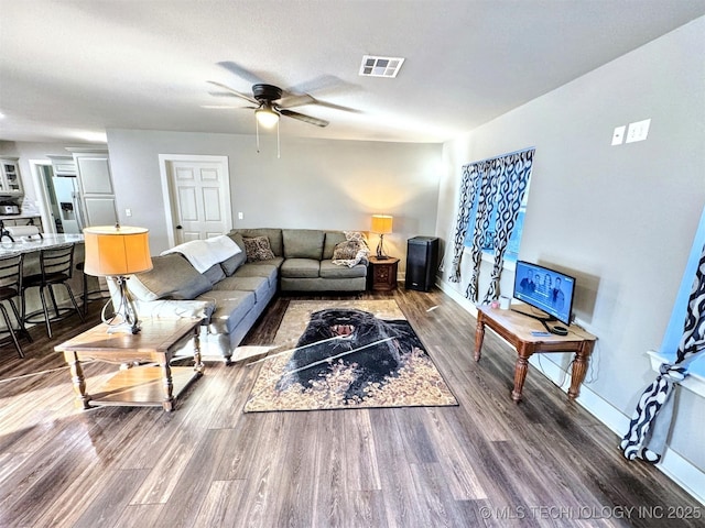 living room with a ceiling fan, baseboards, visible vents, and dark wood-style flooring