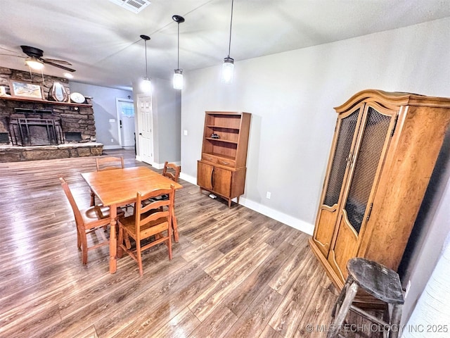 dining space with baseboards, visible vents, ceiling fan, wood finished floors, and a fireplace