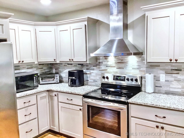 kitchen with a toaster, wall chimney exhaust hood, appliances with stainless steel finishes, light stone countertops, and backsplash