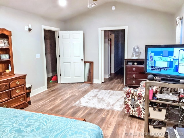 bedroom featuring visible vents, baseboards, vaulted ceiling, and wood finished floors