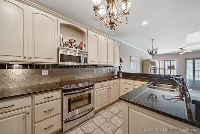 kitchen with sink, appliances with stainless steel finishes, hanging light fixtures, tasteful backsplash, and cream cabinets