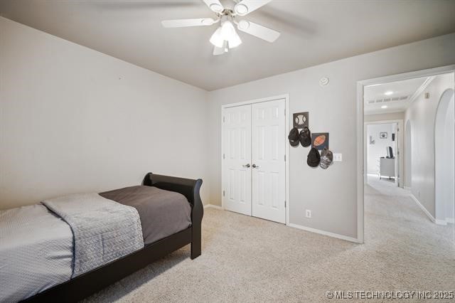 carpeted bedroom featuring ceiling fan and a closet