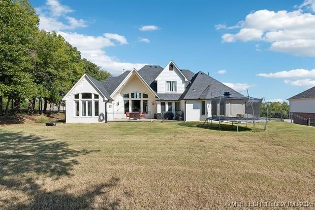 back of property with a trampoline and a lawn