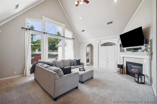 living room featuring ceiling fan, high vaulted ceiling, a tile fireplace, and light carpet