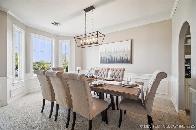 dining area featuring ornamental molding, plenty of natural light, and light colored carpet