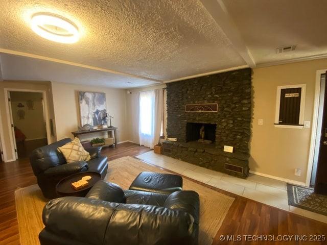 living room featuring a stone fireplace, hardwood / wood-style floors, and a textured ceiling