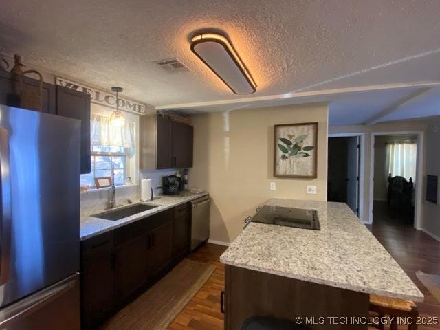 kitchen featuring appliances with stainless steel finishes, sink, a textured ceiling, and dark hardwood / wood-style flooring