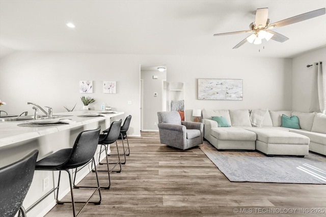 living room featuring sink, ceiling fan, and light wood-type flooring