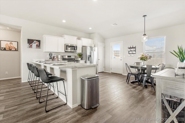 kitchen featuring dark wood-type flooring, white cabinetry, decorative light fixtures, appliances with stainless steel finishes, and light stone countertops