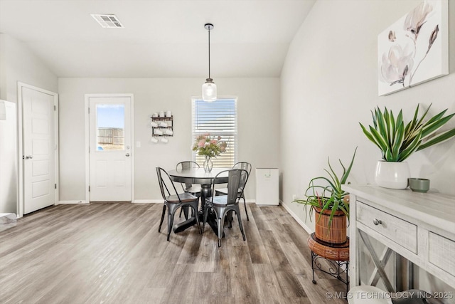 dining room with light hardwood / wood-style floors and vaulted ceiling