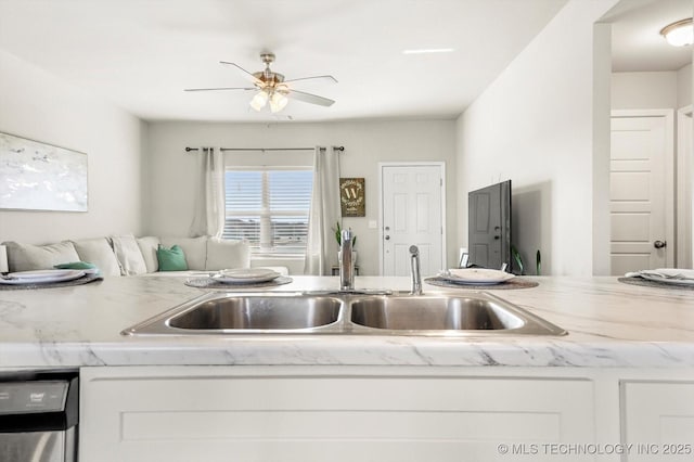 kitchen with sink, dishwasher, white cabinets, and light stone countertops