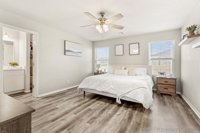 bedroom with multiple windows, ensuite bathroom, ceiling fan, and light wood-type flooring