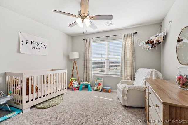 carpeted bedroom featuring a nursery area and ceiling fan