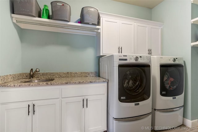 clothes washing area featuring washer and dryer, sink, and cabinets