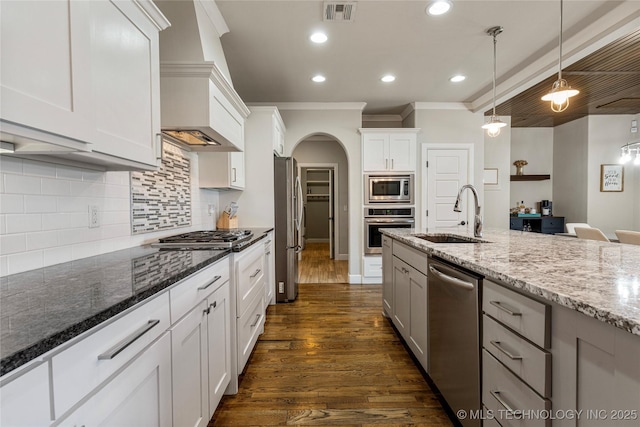 kitchen featuring pendant lighting, tasteful backsplash, sink, white cabinets, and stainless steel appliances