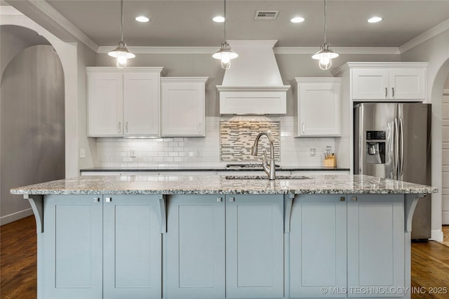 kitchen featuring pendant lighting, white cabinetry, light stone countertops, and an island with sink