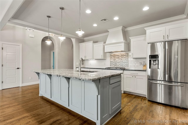 kitchen with a center island with sink, custom exhaust hood, white cabinets, and appliances with stainless steel finishes