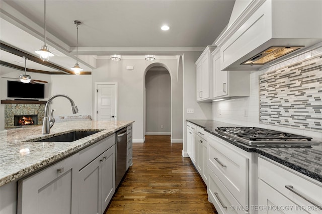 kitchen with white cabinetry, sink, dark stone counters, custom exhaust hood, and stainless steel appliances