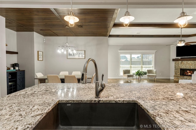 kitchen featuring a fireplace, wood-type flooring, sink, hanging light fixtures, and ceiling fan