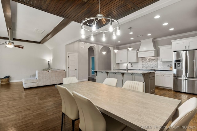 dining room with dark wood-type flooring, ceiling fan, sink, and lofted ceiling with beams