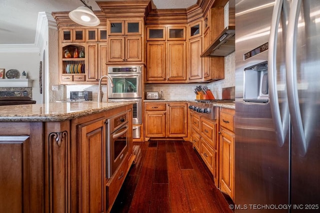 kitchen with pendant lighting, backsplash, ornamental molding, stainless steel appliances, and wall chimney range hood