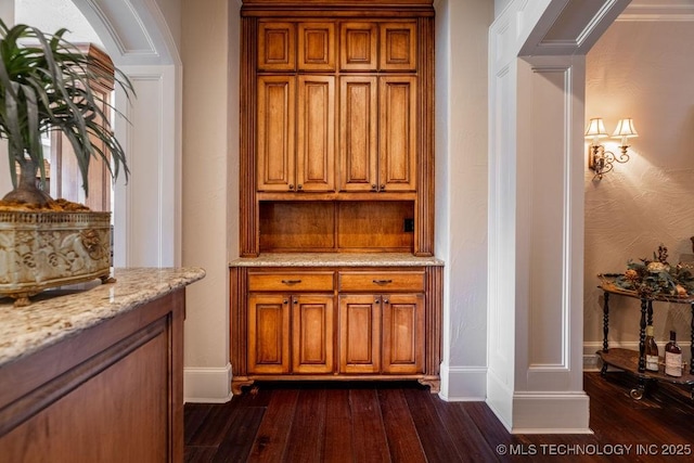 bar featuring ornate columns, crown molding, light stone countertops, and dark hardwood / wood-style floors