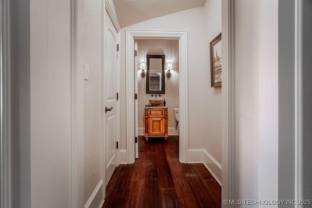 corridor featuring vaulted ceiling and dark wood-type flooring