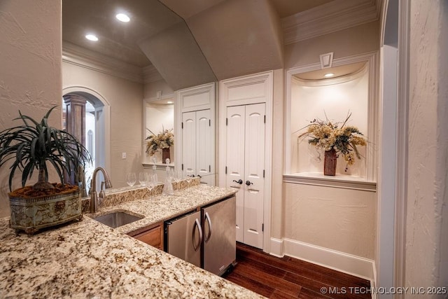 kitchen with dark wood-type flooring, sink, crown molding, dishwashing machine, and light stone countertops