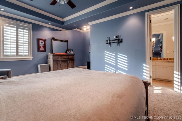 carpeted bedroom featuring sink, ceiling fan, a raised ceiling, crown molding, and ensuite bath