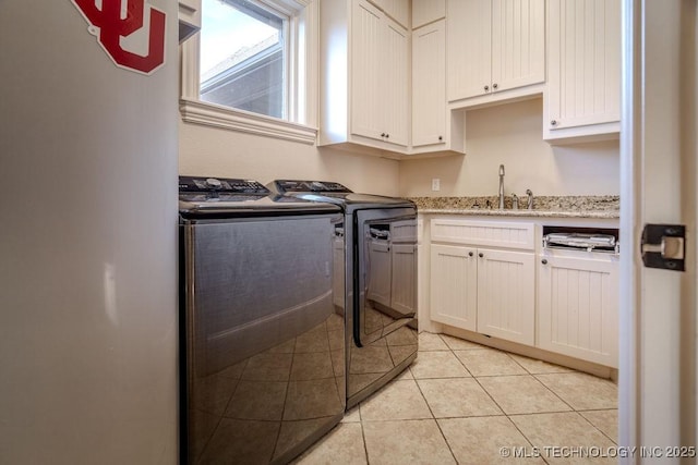 clothes washing area with cabinets, light tile patterned flooring, sink, and washer and clothes dryer