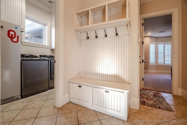 mudroom with washing machine and clothes dryer, ornamental molding, light tile patterned floors, and a wealth of natural light