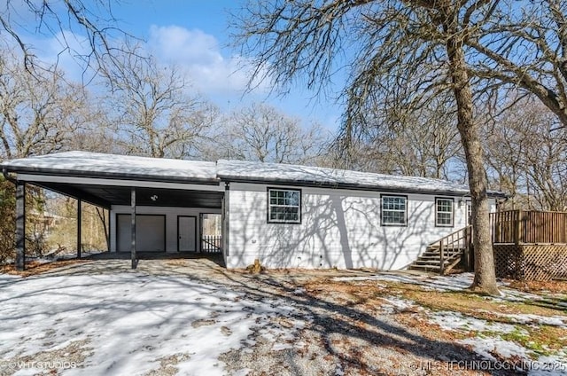 snow covered structure featuring a garage and a carport