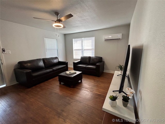 living room featuring ceiling fan, a wall mounted air conditioner, dark hardwood / wood-style flooring, and a textured ceiling