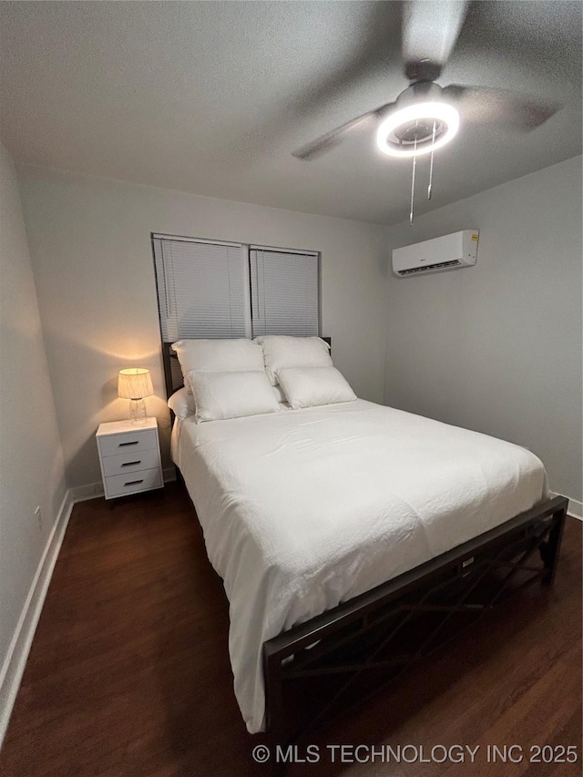 bedroom with dark hardwood / wood-style flooring, a wall unit AC, a textured ceiling, and ceiling fan