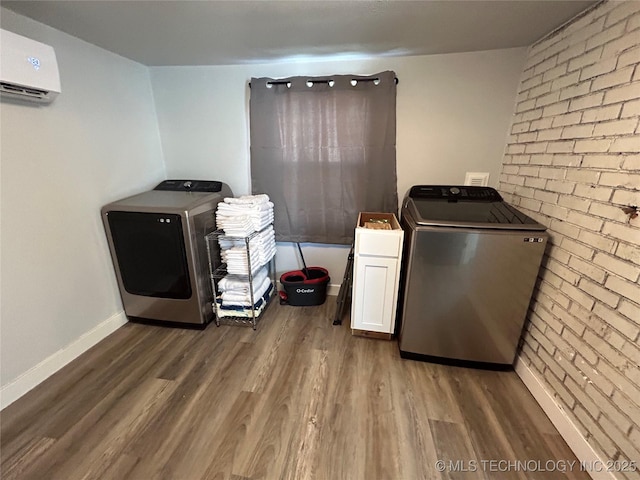 washroom featuring cabinets, brick wall, a wall unit AC, and washer and clothes dryer